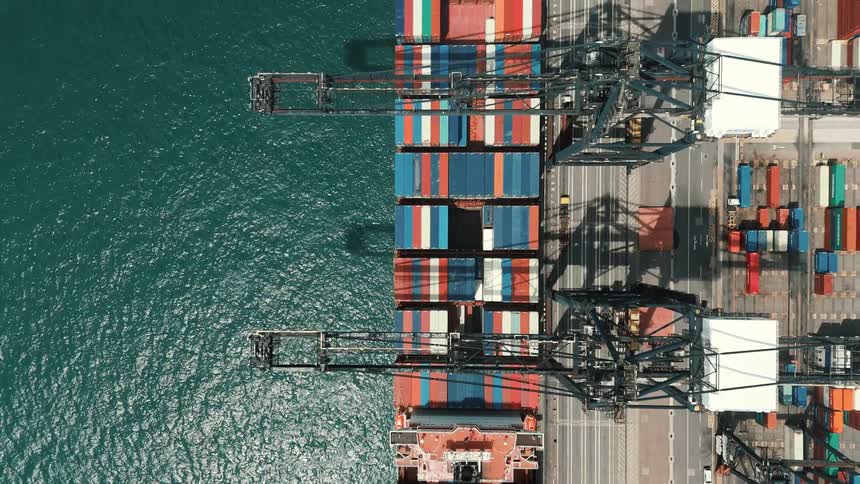 Aerial view of a port crane loading colorful containers onto a ship