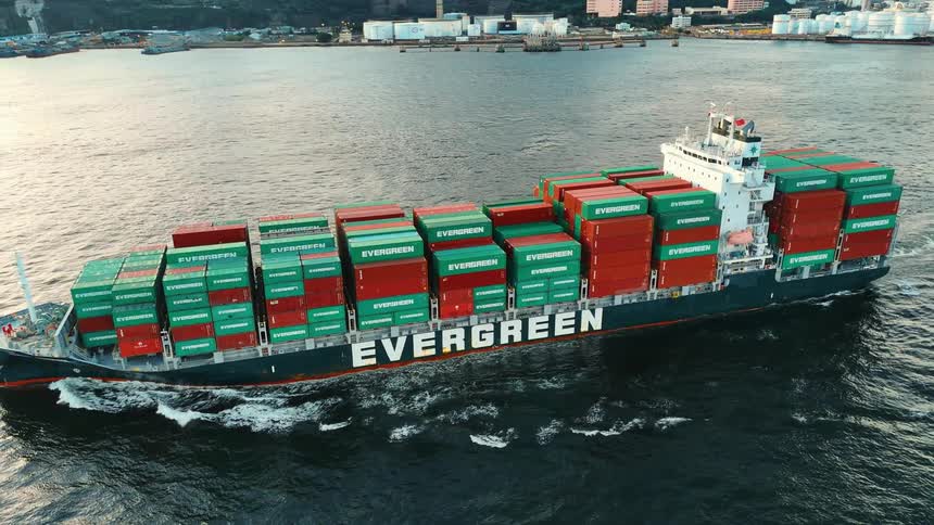 A container ship operated by evergreen marine corporation sailing on the ocean near the shore at midday