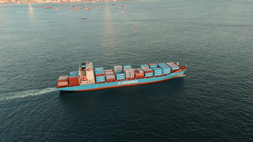 Crates stacked on a cargo ship sailing on the water off the coast