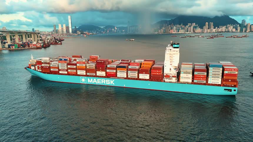 Aerial of a loaded cargo shop on a body of water close to a metropolitan city during daytime