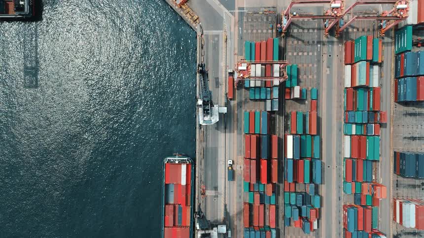Aerial view of a port with colorful containers lined up and ships docked alongside the quay