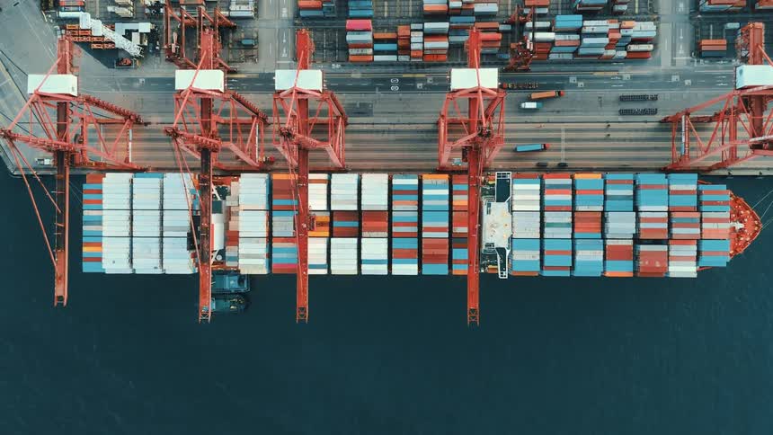Aerial view of a container ship being loaded by cranes at a port terminal