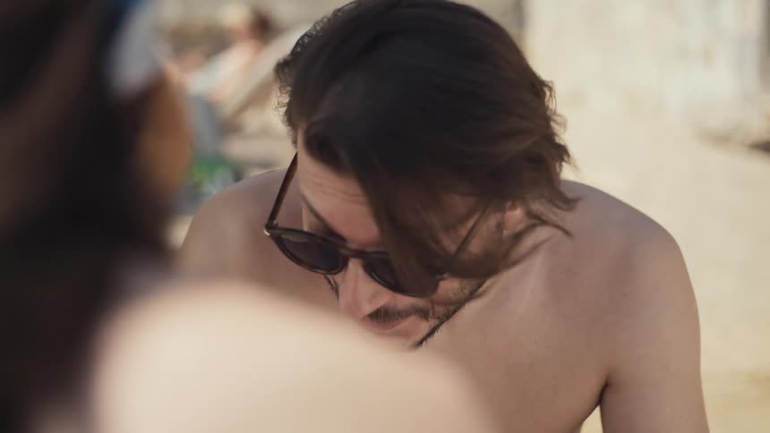 Couple sunning outdoors faces each other on a breezy summer day