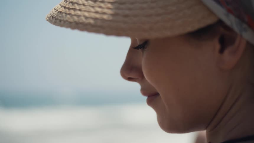 Woman in a straw hat seen in closeup by the sea