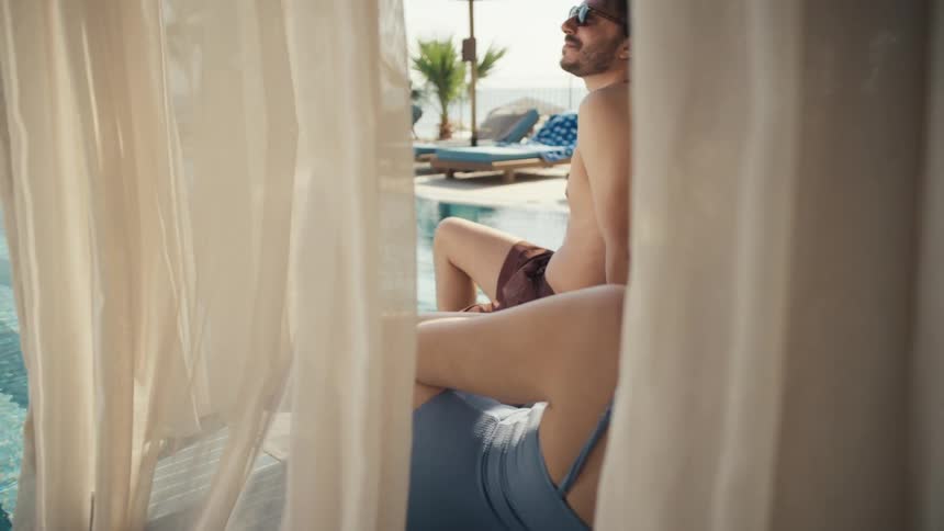 Man and woman relax in a resort cabana by the pool