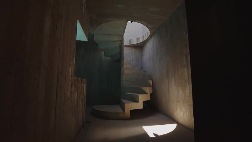 Concrete spiral staircase illuminated by beams of natural light