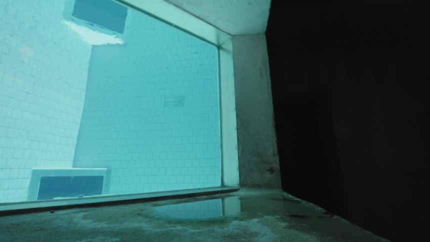 Underwater window reveals a view of a whitetiled pool