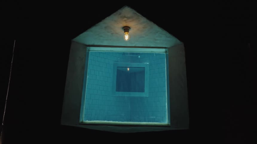 A ceiling light turns on inside a building and then goes off afterward at night