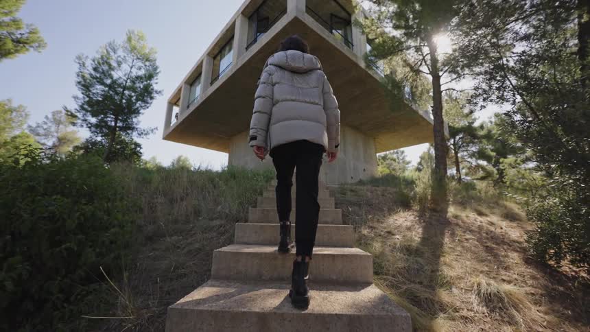 The woman climbs the steps towards her home