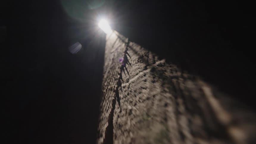 A beam of sunlight pierces through darkness highlighting the deep grooves of a rough dirt surface