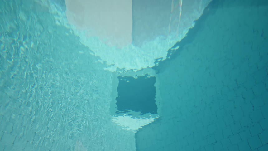 Underwater view showing the wall and drain of a blue swimming pool