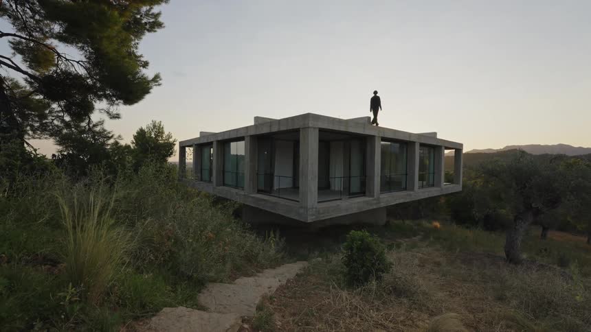 A man walking on the roof of a building surrounded by green vegetation at midday