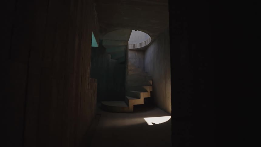 The video shows a dark narrow hallway with a spiral staircase at the end a small patch of sunlight illuminates the bottom of the stairs