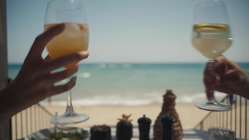 A couple toast their drinks on the beach