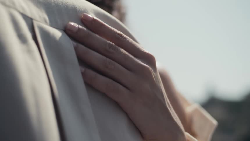 A closeup shot focuses on a persons hand gently caressing the shoulder of another person highlighting a moment of intimate and tender physical affection