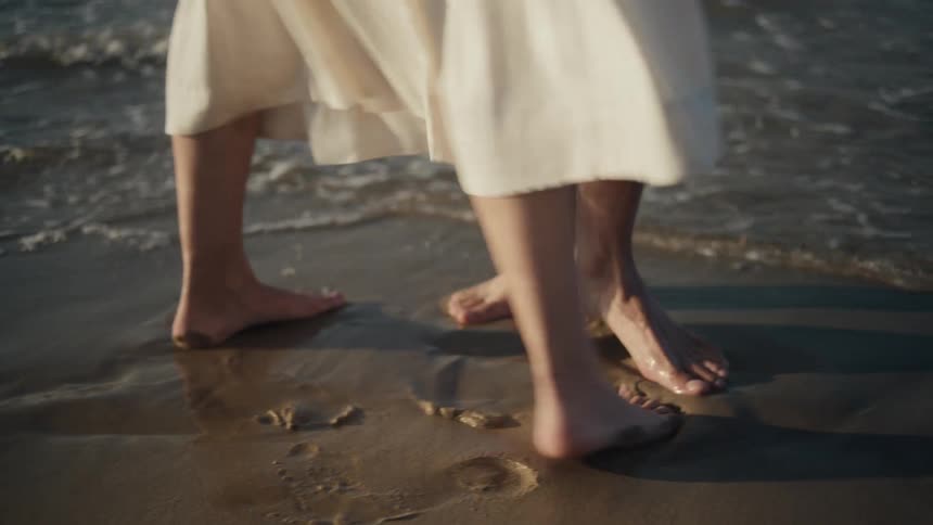 A couple barefoot on the beach having fun at midday