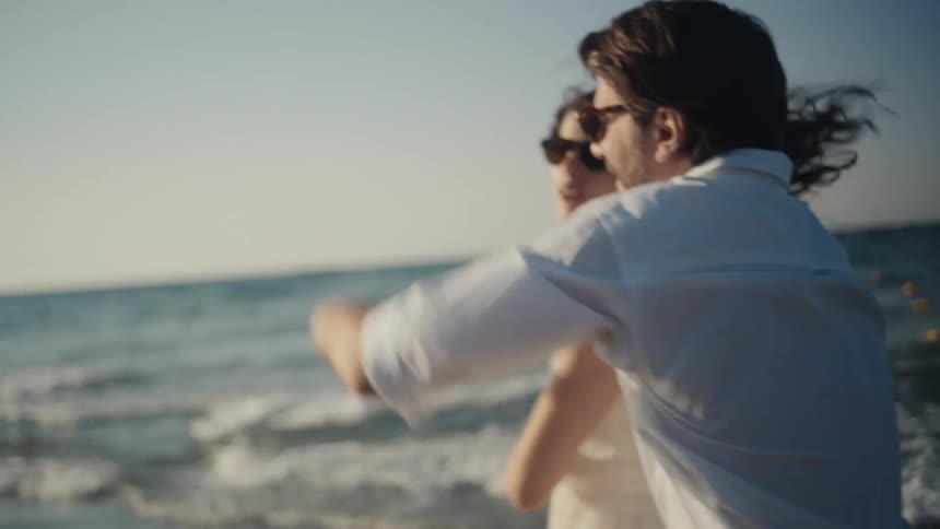 Couple dances by the seaside wearing sunglasses