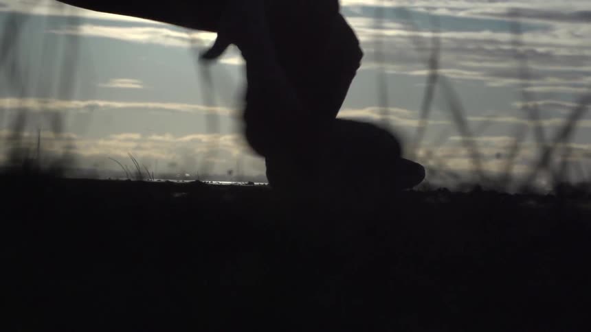 Close up of person's feet and legs as the break dance and kick up dirt