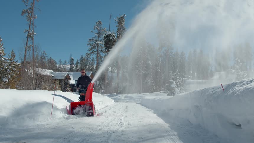 Man with a machine removing snow from a road