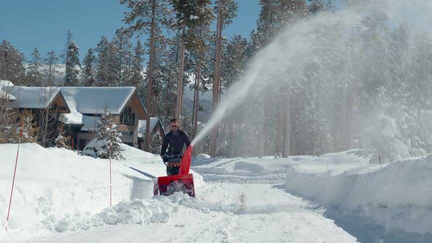 A man uses a snowblower