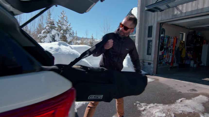Man storing a suitcase in the trunk of a car