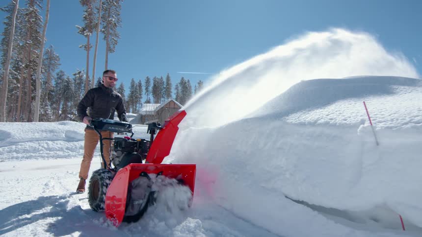 Man driving a machine and removing snow from the path