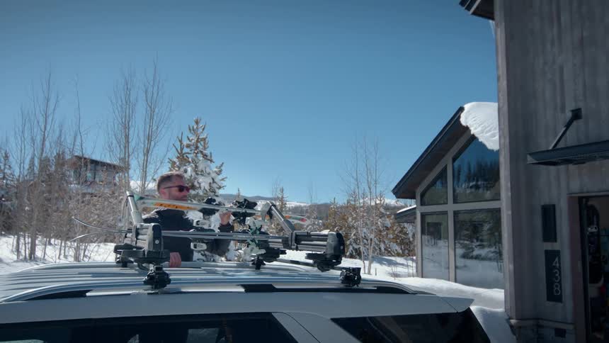 Man placing a stand on top of a car