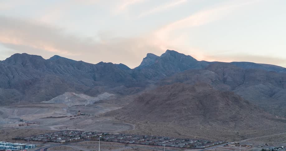 A small town surrounded by tall mountains at midday