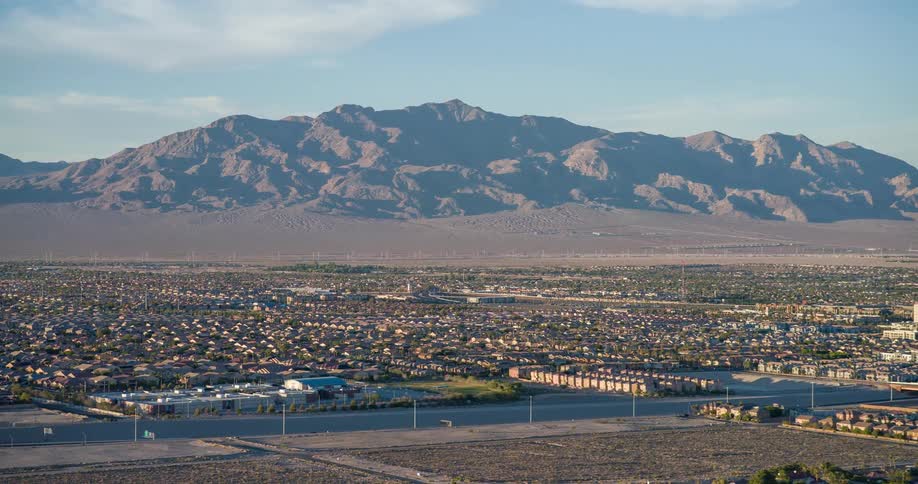 A city with a series of buildings and a mountain in the background at midday