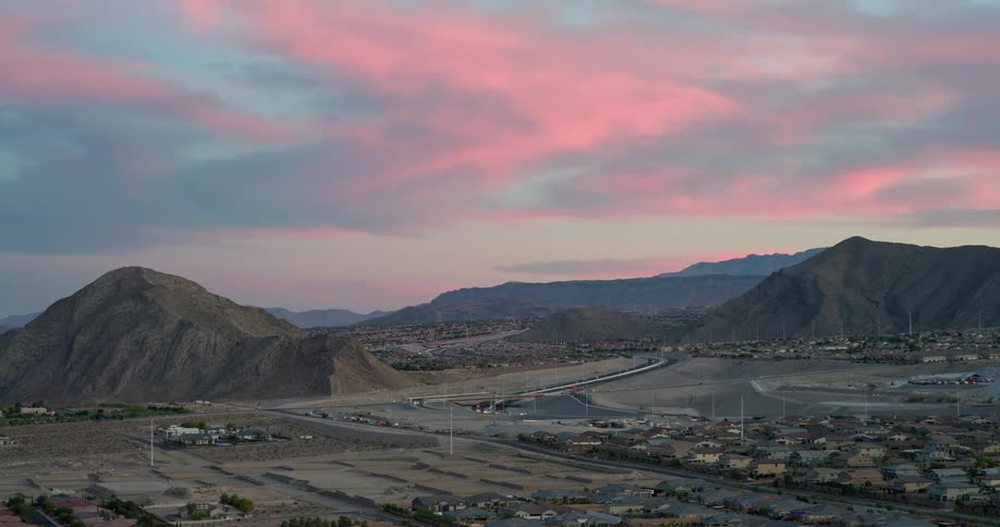 Urban houses in an area surrounded by mountains against a reddish sky