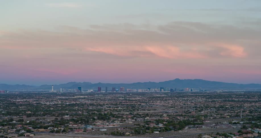 City skyline at sunset with a series of buildings silhouetted against the sky as orange clouds spread across the horizon