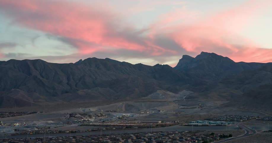 A small town surrounded by mountains with an orange sky overhead