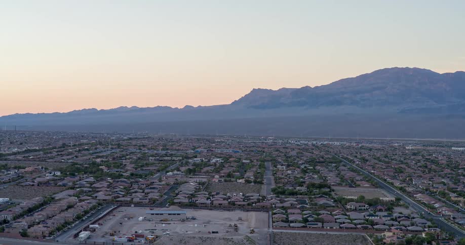 A city skyline with residential buildings and a mountain range in the background at midday
