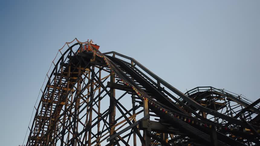 A roller coaster with people riding it in an amusement park at golden hour