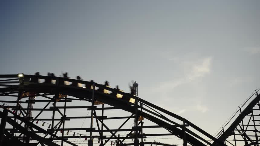 A vintage amusement park with a roller coaster and other fun rides at sunset