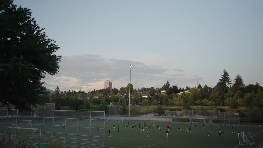 A large group of people wearing different colored jerseys playing football on a football field after work