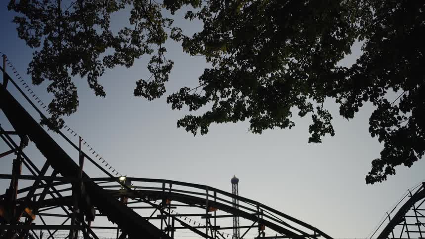 An amusement park with a series of rides at sundown in the city