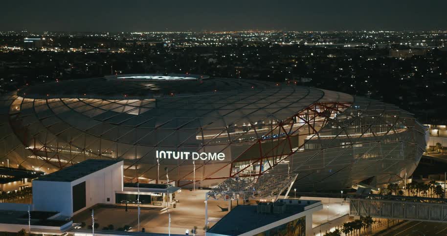Aerial shot of a stadium lit up by a city at night