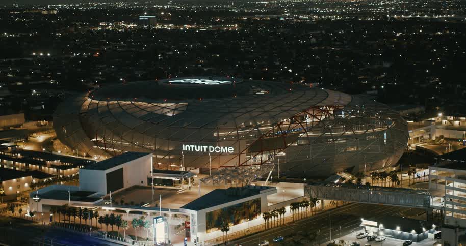 Cars driving past a basketball arena at night