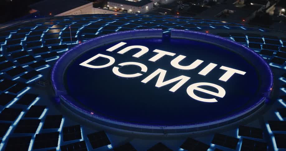 Letters in the intuit dome label at the top of the sports venue contrast with its blue background during the evening