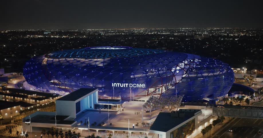 Intuit dome stadium lit in blue stands out at night under the full moon