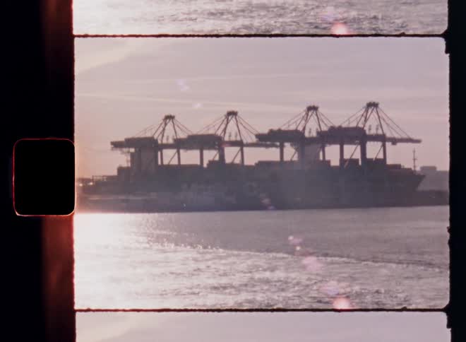 Cargo ship and industrial cranes seen through vintage film