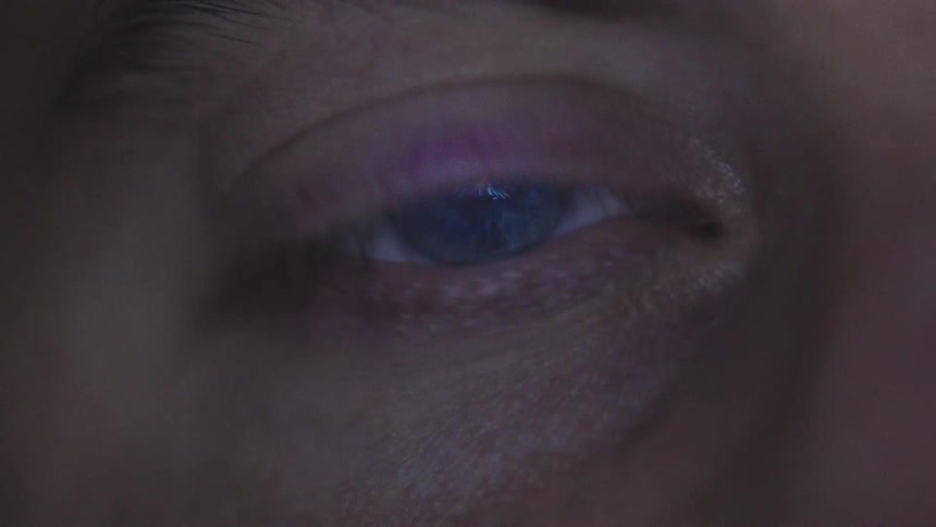 Blue eye reflects a luminous pattern resembling an energy field