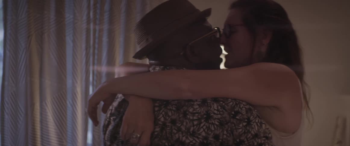 A man and woman hug near a lamp