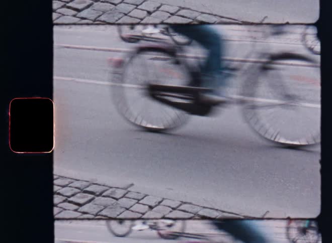 People riding their bikes on a busy city road at midday