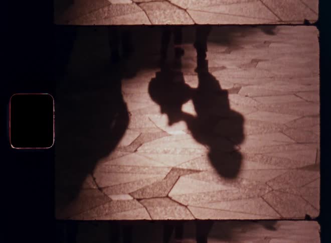 Two kids holding hands as they walk down the street at sundown