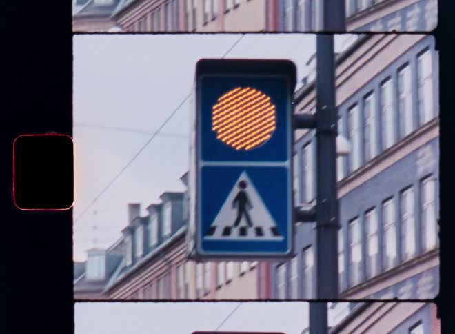 Pedestrian crossing sign with an orange traffic light illuminated