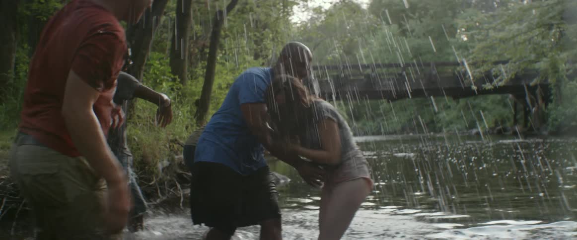 A group of people pull a woman into a river and splash her
