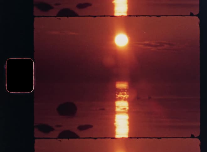 A vivid redorange sunset reflects over calm ocean waters in a nostalgic filmstyle frame