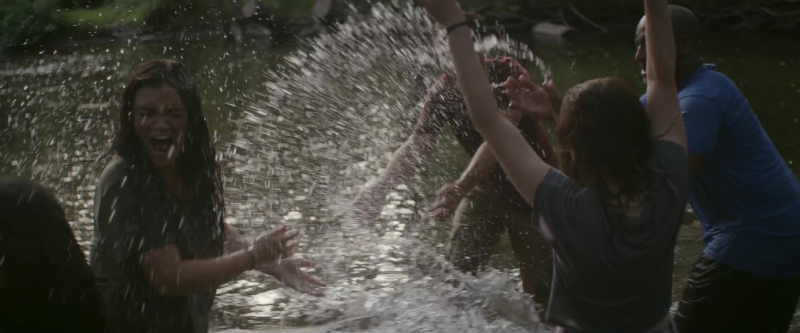 A group of people splash in a shallow river